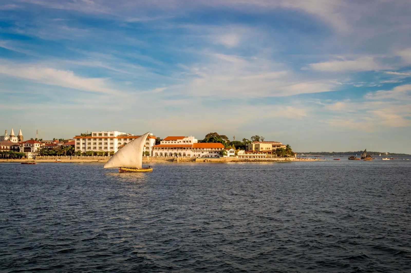 Dhow sailing past the Stone Town seafront in late afternoon light