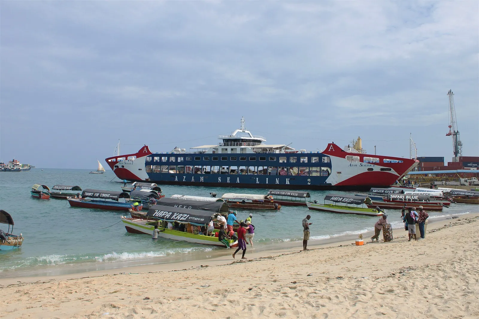 Big Tree beach in Stone Town with small boats and the ferry at the terminal behind