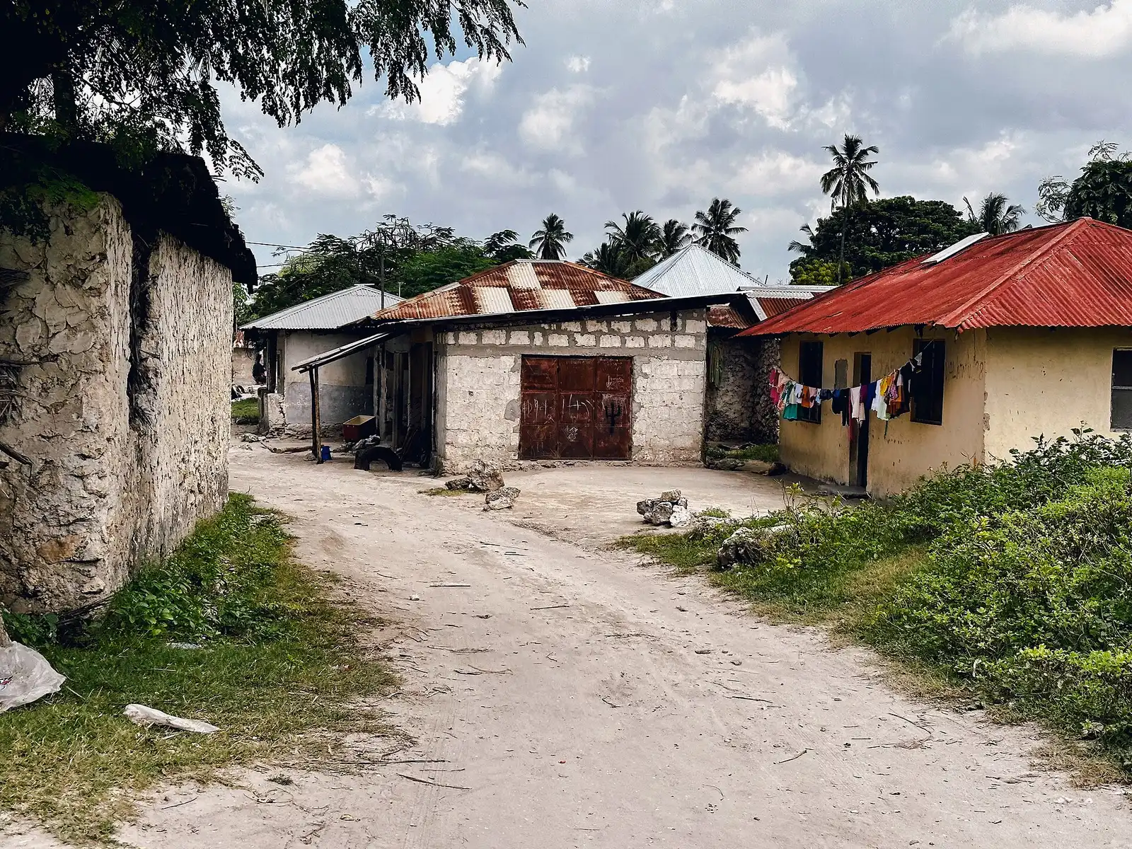 Sandy lane between coral-stone houses with tin roofs in Matemwe