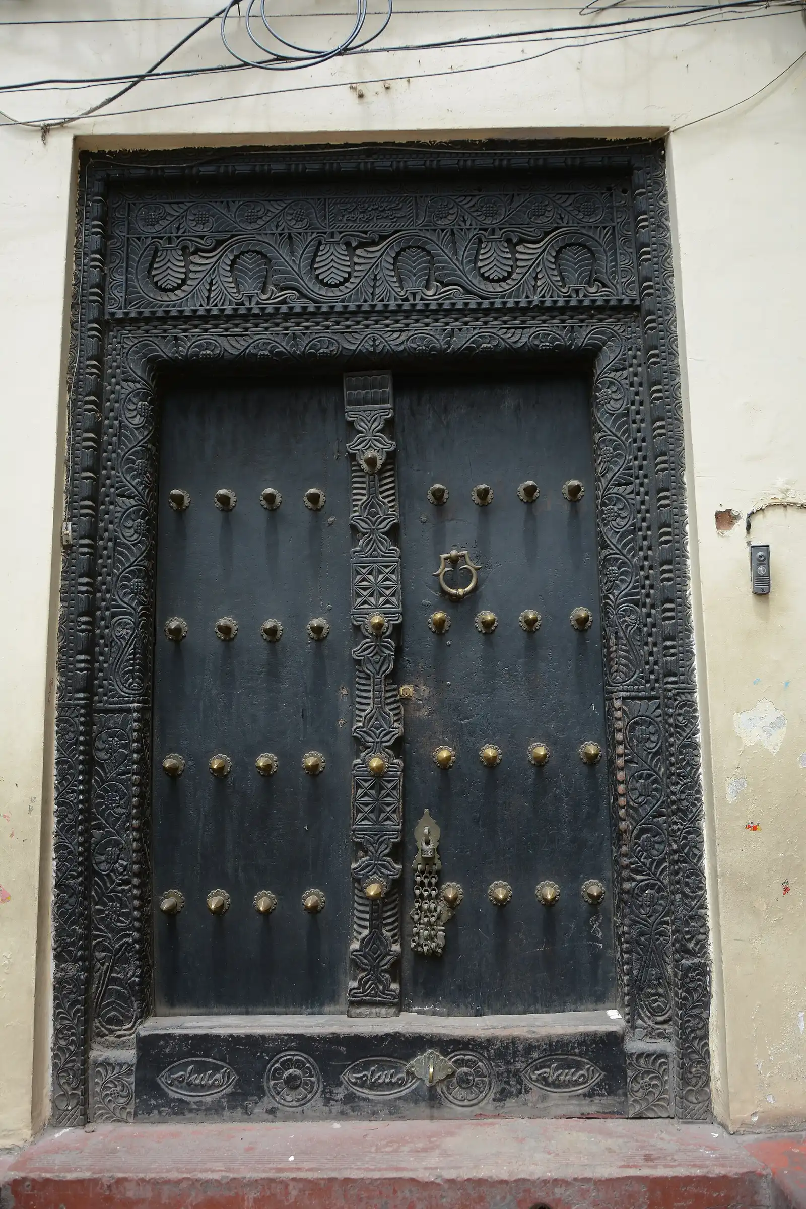 Dark carved Arab-style wooden door with brass studs in Stone Town
