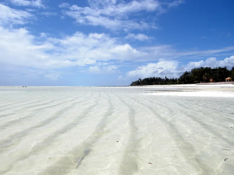Paje beach at low tide, rippled white sand under clear shallow water