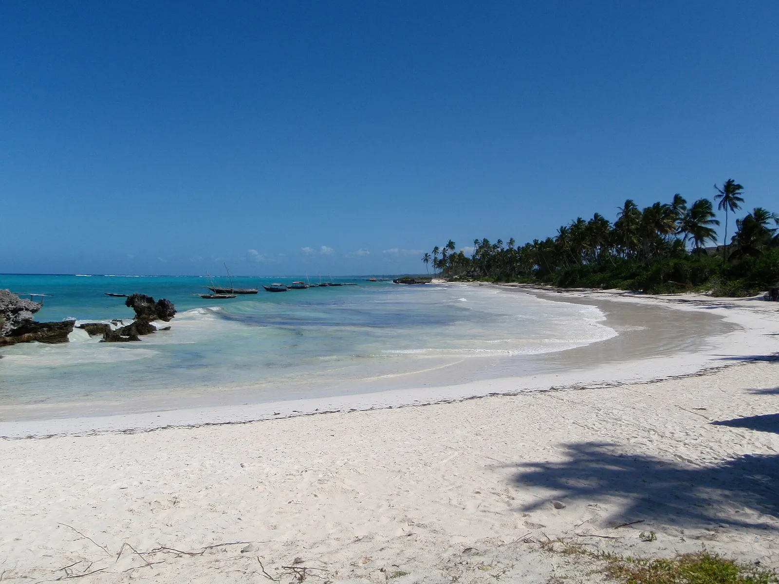 Matemwe beach with coral rocks, moored boats and a line of palms