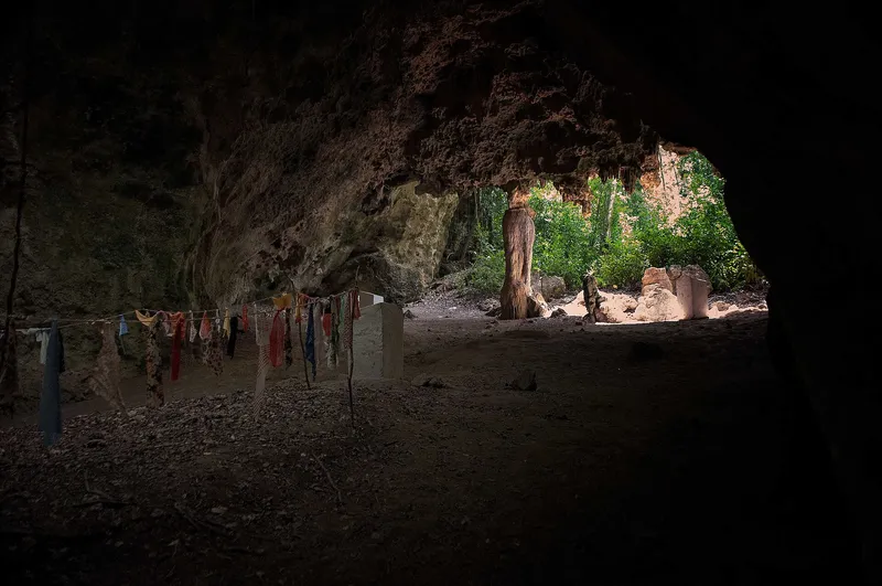 Inside Kuumbi Cave, with offering cloths on a line and daylight at the entrance
