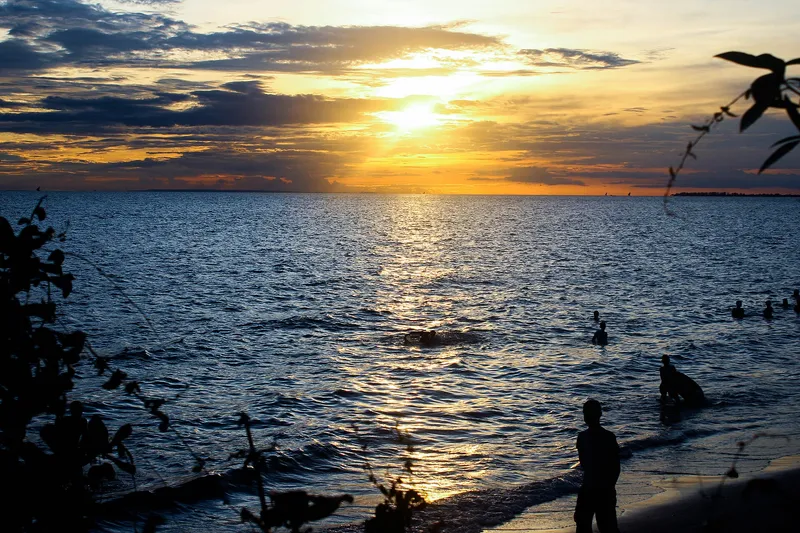 Sunset over the sea off Zanzibar with swimmers in silhouette