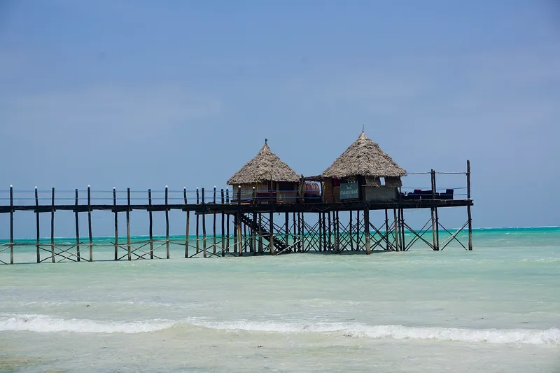 Thatched bar on stilts at the end of a wooden jetty over the lagoon at Jambiani