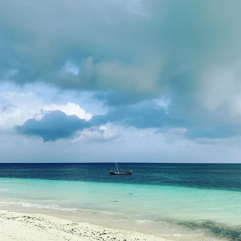 Rain clouds over the sea and a moored dhow off Nungwi beach